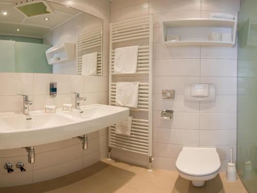 a bathroom with two sinks and a toilet at Familien- & Vitalhotel Auenhof in Fulpmes