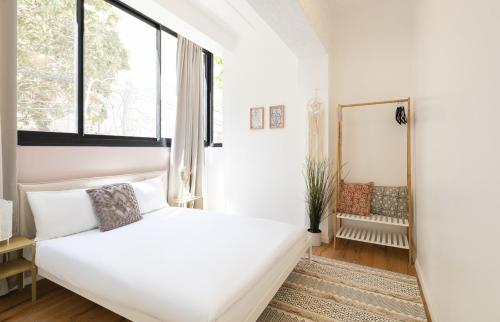 um quarto branco com uma cama e um espelho em Near the beach & modern em Tel Aviv