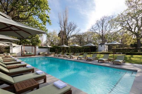 a swimming pool with chaises and chairs next to at The Alphen Boutique Hotel & Spa in Cape Town