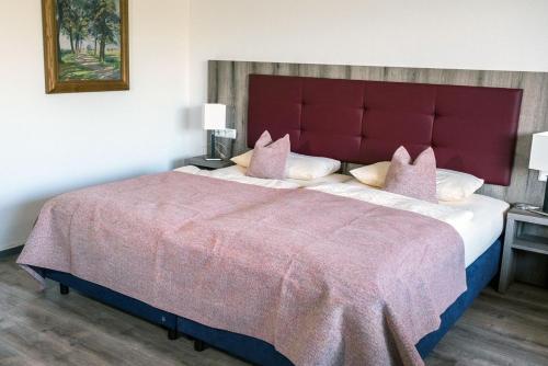 sypialnia z dużym łóżkiem z czerwonym zagłówkiem w obiekcie Galeriehotel Maribondo w mieście Worpswede