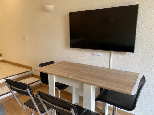 a table with chairs and a flat screen tv on a wall at Lovely studio - heart of Menton, near the beach. in Menton