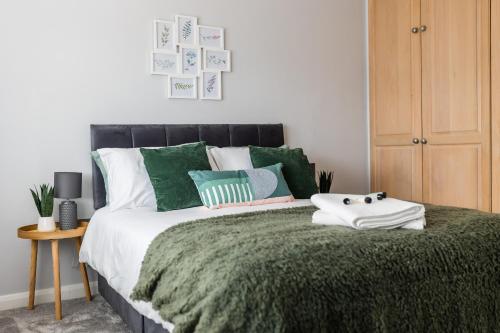 a bedroom with a bed with green and white pillows at Lovely House in Welwyn with Garden and Off road parking in Welwyn Garden City