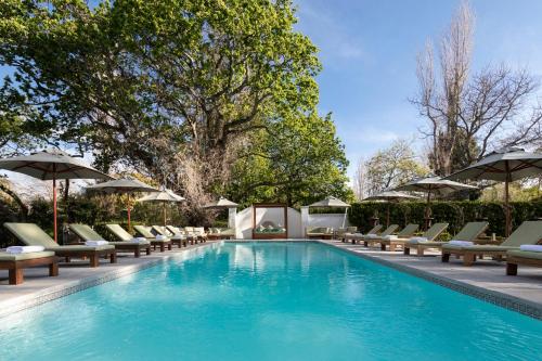 a swimming pool with lounge chairs and umbrellas at The Alphen Boutique Hotel & Spa in Cape Town