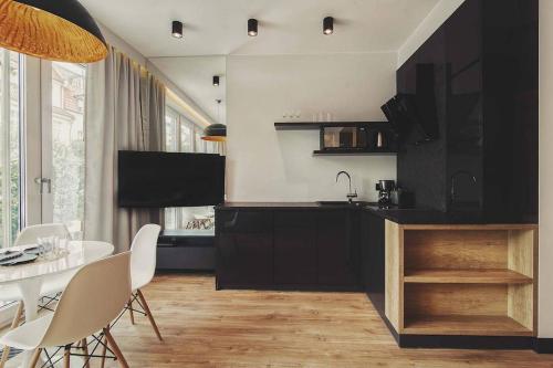 ソポトにあるMontevideo Centrum 2 by Grand Apartmentsのキッチン(黒いキャビネット、テーブル、椅子付)