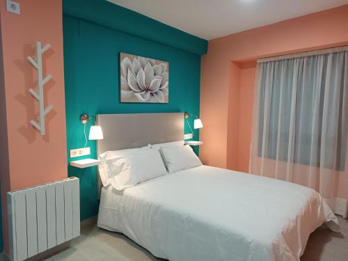 a bedroom with a white bed and a blue wall at Estudios La Casina in Cáceres