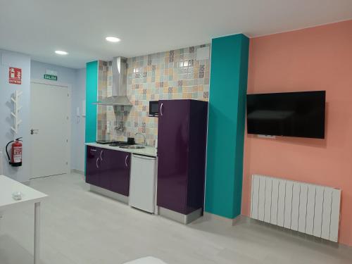 a kitchen with a purple refrigerator and a tv at Estudios La Casina in Cáceres