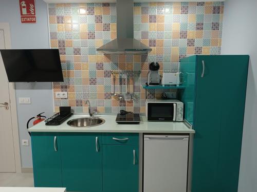 Una cocina con un refrigerador verde y un fregadero. en Estudios La Casina, en Cáceres