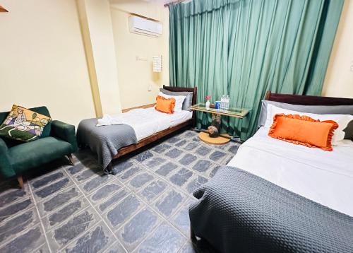 a hotel room with two beds and a chair at Hotel Darwin in Kathmandu