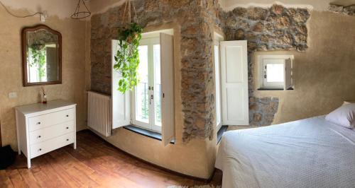 een slaapkamer met een bed en 2 ramen en een spiegel bij Casa Olivia Lacremà in Finale Ligure