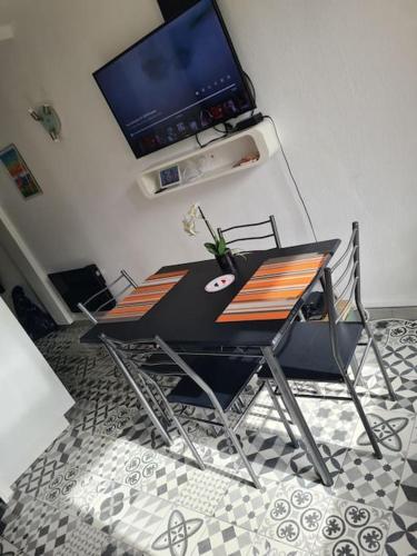 a dining table and chairs with a television on the wall at Appartement Cosy Saint Cyprien in Saint-Cyprien