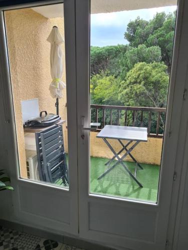 a door to a balcony with a table and a chair at Appartement Cosy Saint Cyprien in Saint-Cyprien