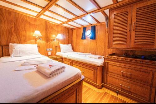 a boat room with two beds and wooden cabinets at Hka Neta Yachting in Fethiye