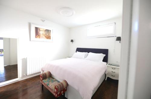 een witte slaapkamer met een bed en een stoel bij "Fall in love only" Morcote lake in Morcote