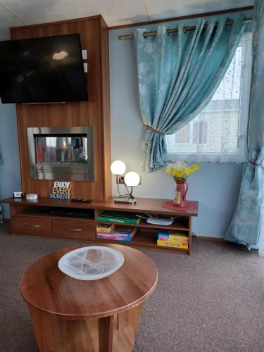 sala de estar con mesa y TV en Vista Caravan Hire en Seasalter