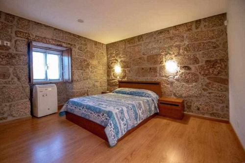 a bedroom with a bed in a room with stone walls at Casa da Boavista Camélias de BastoTurismo Rural in Celorico de Basto