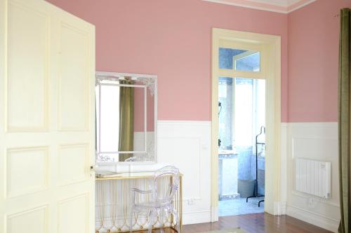 um quarto com paredes cor-de-rosa, um espelho e uma cadeira em Villa Várzea - Garden Suite na Várzea