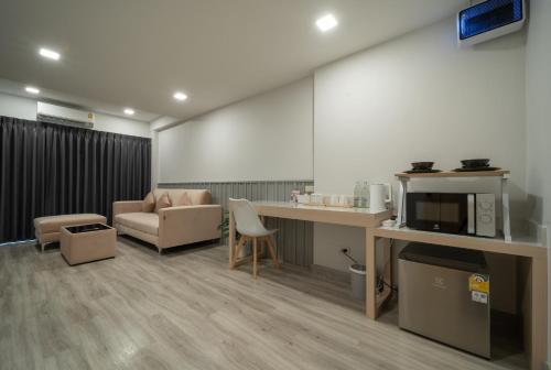 Cette chambre comprend un bureau, un four micro-ondes et un canapé. dans l'établissement The Space Hotel Lampang, à Lampang