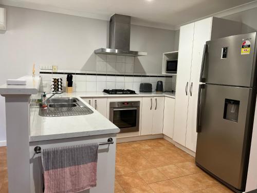 cocina con armarios blancos y nevera de acero inoxidable en Free secure parking & WiFi in this Executive 3 BR., en Kalgoorlie