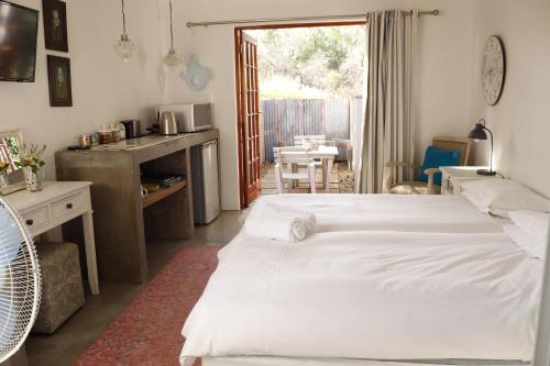 a bedroom with two beds and a kitchen with a table at Pepper Tree Guesthouse in Bloemfontein