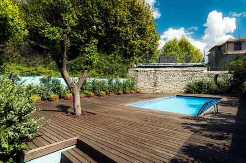 een zwembad met een boom op een houten terras bij Swimming Pool Luxury House 1 in Porto