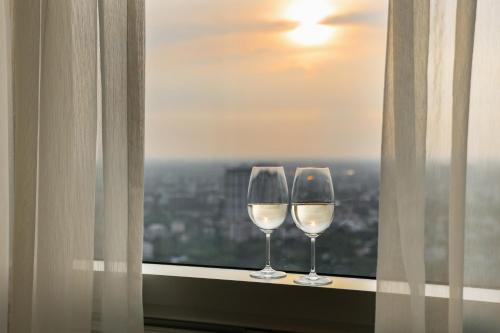 two wine glasses sitting on a window sill with a view at LOTTE Hotel Serviced Apartment in Yangon
