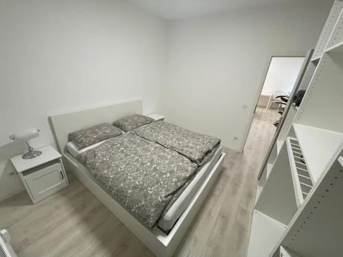 a small white bedroom with a bed and a mirror at Ferienwohnung Edi in Mülheim an der Ruhr