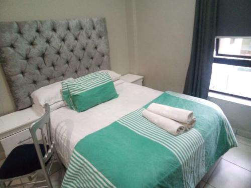 1 dormitorio con 1 cama con 2 toallas en The Rosebank Mall Place, en Johannesburgo