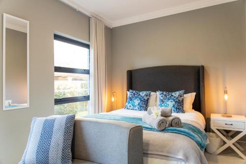 a bedroom with a bed with blue pillows and a window at 2 On Lismore Guesthouse in Tokai