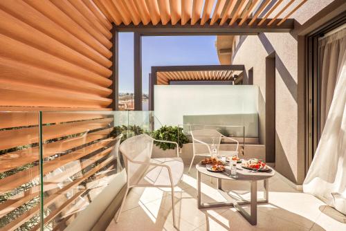 a room with a table and chairs on a balcony at Nautilux Rethymno by Mage Hotels in Rethymno Town