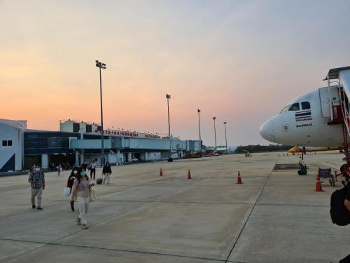 a group of people walking around an airport with an airplane at The 8 Factory Hotel Phitsanulok in Phitsanulok