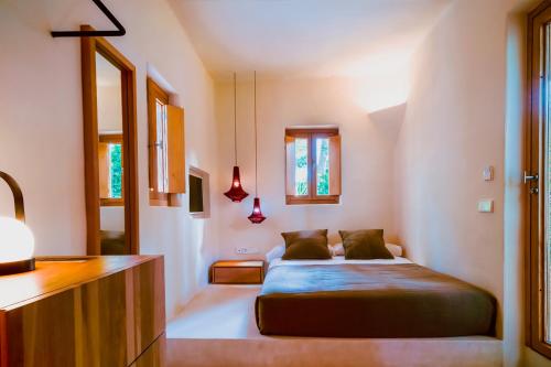 a bedroom with a bed and two windows at Casbah Formentera Hotel & Restaurant in Playa Migjorn