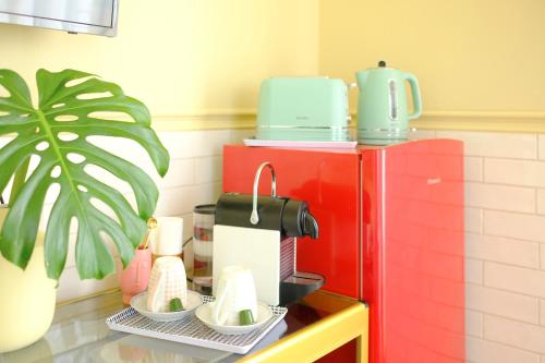 a coffee maker on a shelf next to a red refrigerator at Villa Várzea - Garden Suite in Várzea