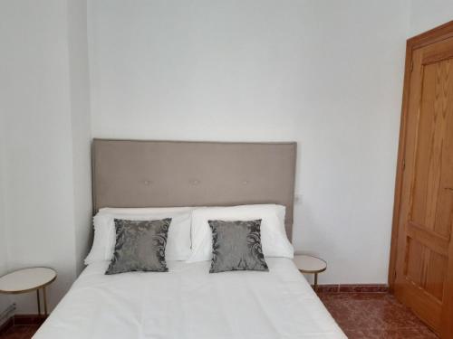 um quarto com uma cama branca e 2 almofadas em El Fuerte em Benamaurel