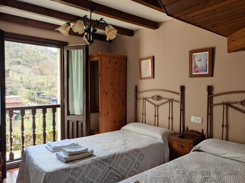 1 dormitorio con 2 camas y balcón en El Cantón, en Cangas de Onís