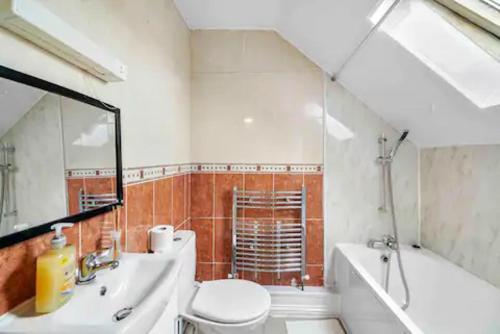 La salle de bains est pourvue d'un lavabo, de toilettes et d'une baignoire. dans l'établissement 4 bed Townhouse- Free parking, à Londres