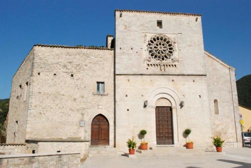 un antiguo edificio de piedra con una torre de reloj en La casa di Carlotta, en Cerreto di Spoleto