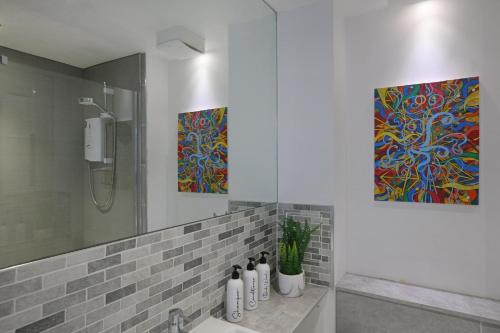 a bathroom with a shower and two paintings on the wall at Spacious 4BR City Centre Apartment w/ Free Parking in Edinburgh