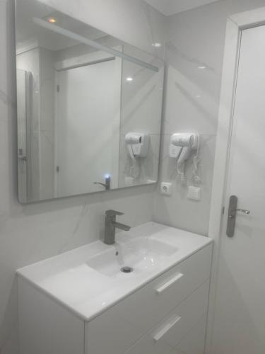 a white bathroom with a sink and a mirror at Limin Hostel Capsules in Valencia
