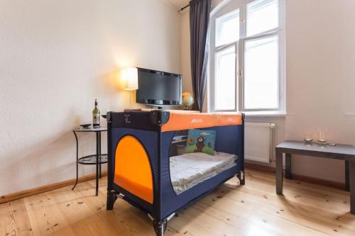 a small room with a bed with a tv on it at Zentrale Altbauwohnung im Helmholtzkiez in Berlin