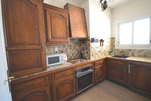 - une cuisine avec des placards en bois et un four micro-ondes dans l'établissement Charming Stanislas Studio with Wi-Fi and Air Conditioning, à Cannes