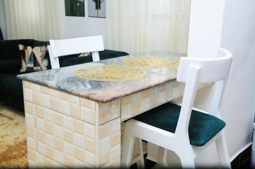 une table avec deux chaises blanches et un comptoir dans l'établissement Igwe Homes - Kisaasi, à Kampala