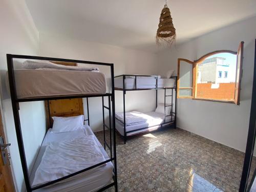a room with three bunk beds and a mirror at Sable beach surf camp taghazout in Taghazout