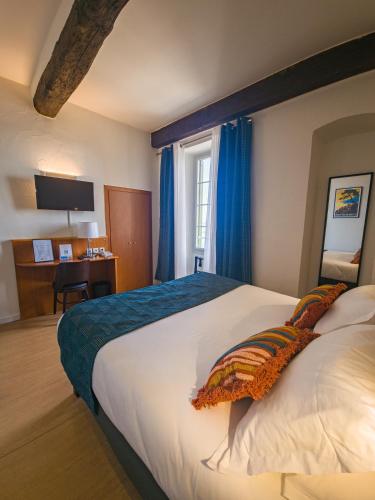 a bedroom with a large bed with blue curtains and a desk at Hôtel Posta Vecchia in Bastia