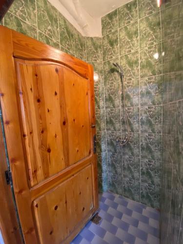 a bathroom with a wooden door and a shower at Sable beach surf camp taghazout in Taghazout