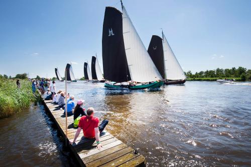 a group of people sitting on a dock watching sailboats at Bella Porto in Eernewoude