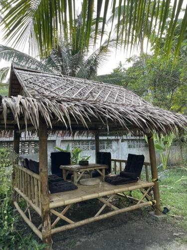 a hut with chairs and a table with a thatched roof at Mythai Guesthouse in Chaloklum