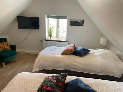 a bedroom with two beds and a chair and a television at Ledvogterhuset B&B in Faxe