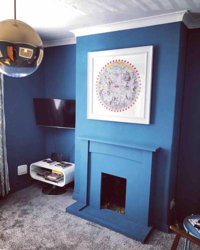a room with a blue wall with a fireplace at Handbridge in Chester sleeps 7 with BT Sports & Pac-man in Hough Green