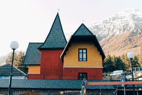 a red and yellow building with a mountain in the background at La Villetta Food & Drink Rooms for Rent - No Reception - in LʼAquila