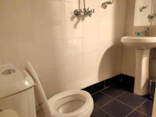 La salle de bains est pourvue de toilettes blanches et d'un lavabo. dans l'établissement Melvic Hotel, à Kisumu